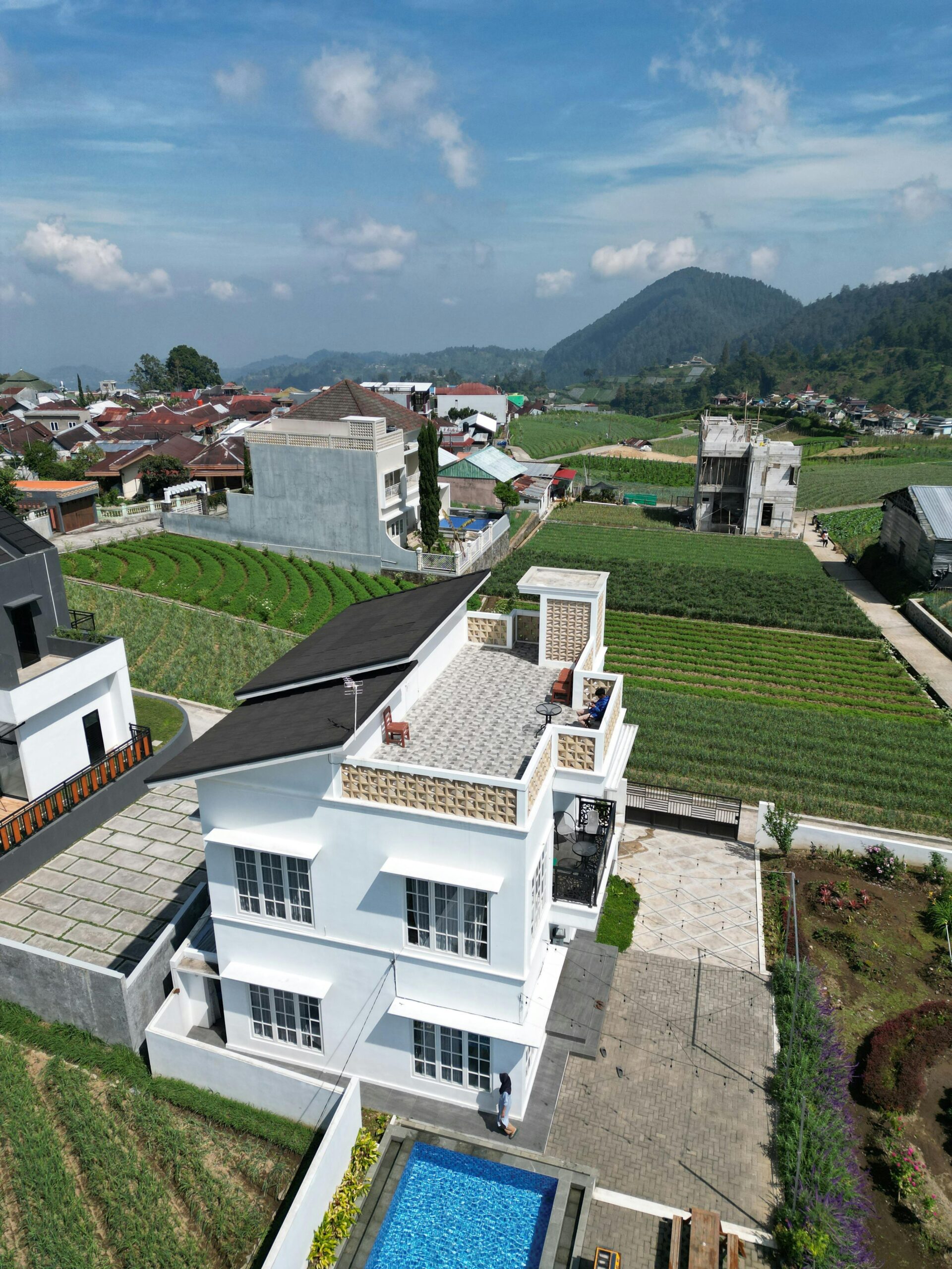 Aerial view of a modern home with pool amidst scenic rural landscape and farmland.