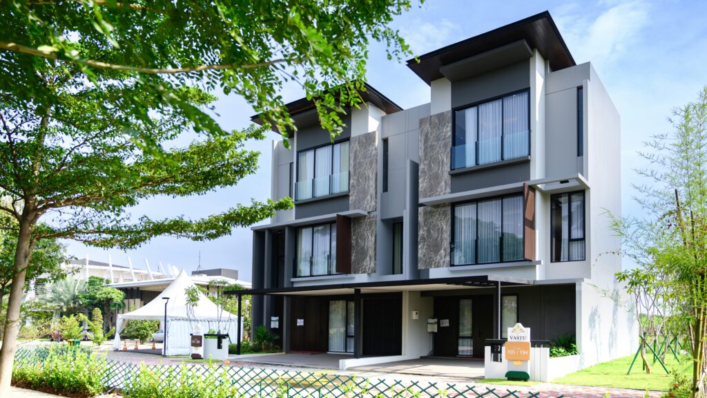 Contemporary three-story residential building set amidst lush green landscape on a clear day.